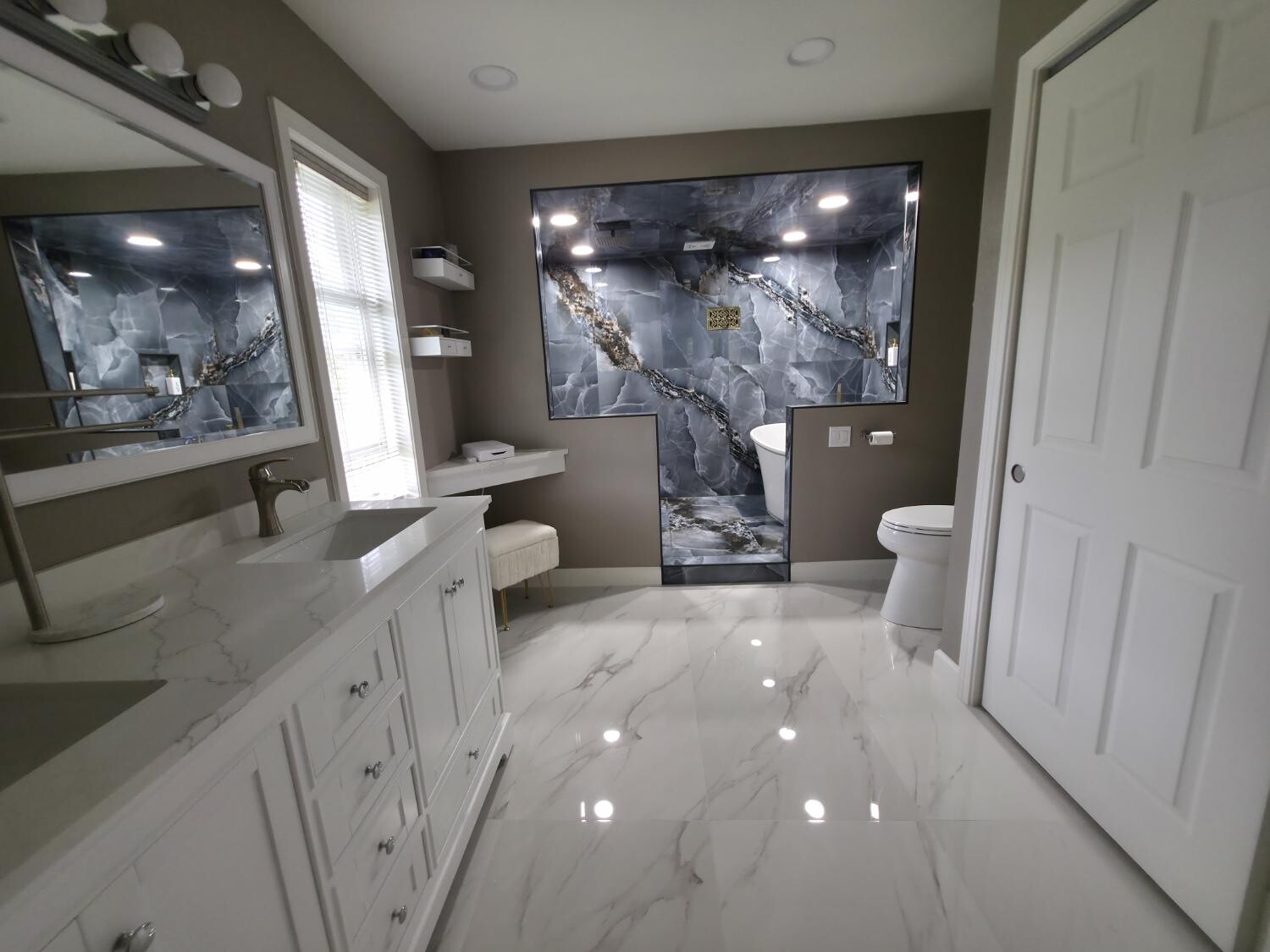 White vanity and marble floor facing the wet room