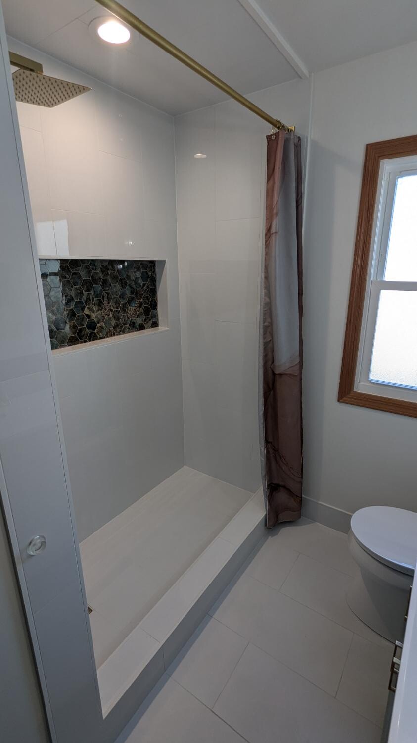 White tiled shower with gold rod and hex niche