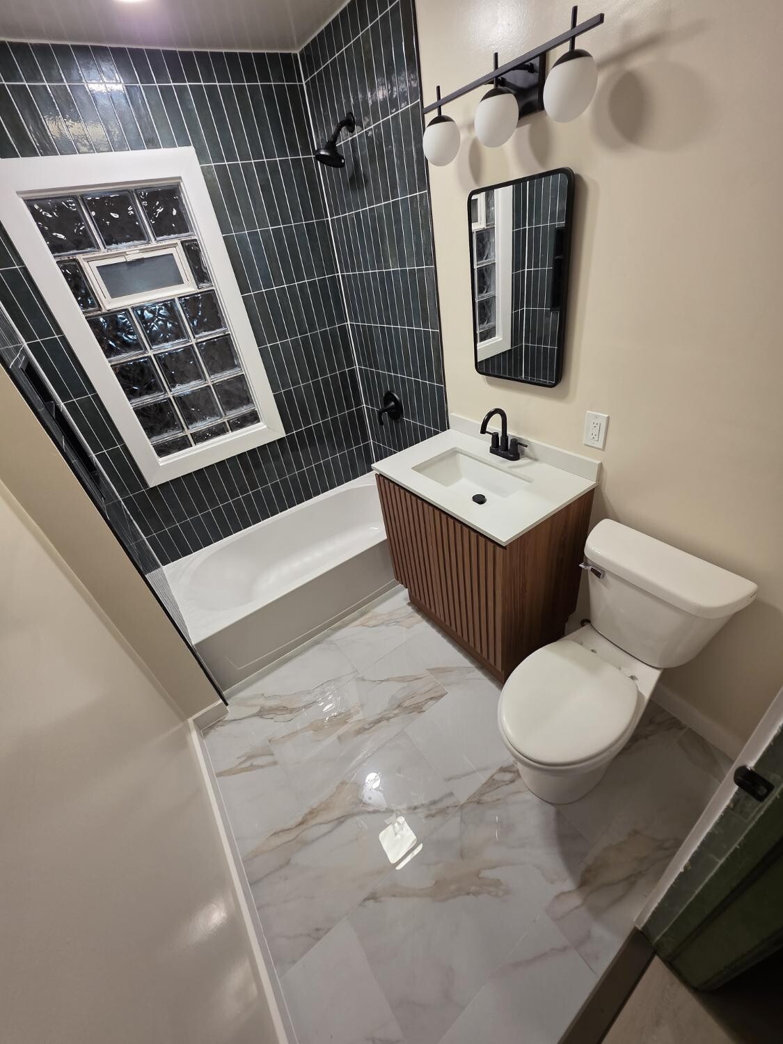 Full green tile bath with marble floor