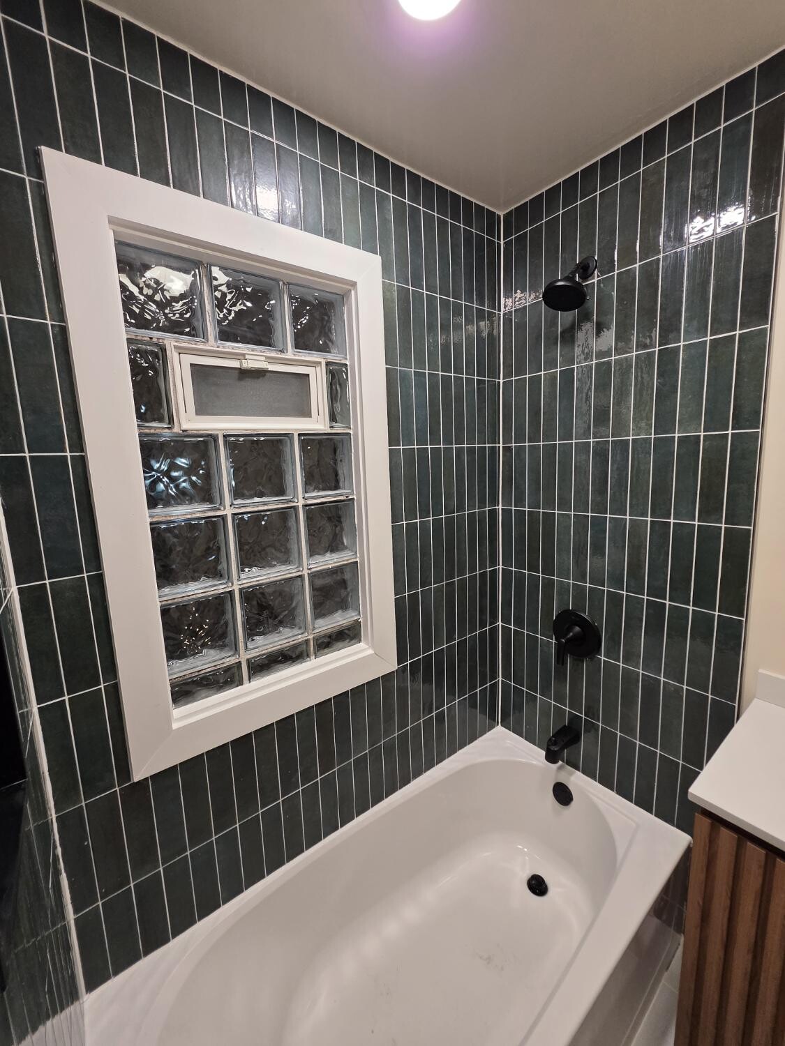 Green stacked tile around the tub and glass-block window