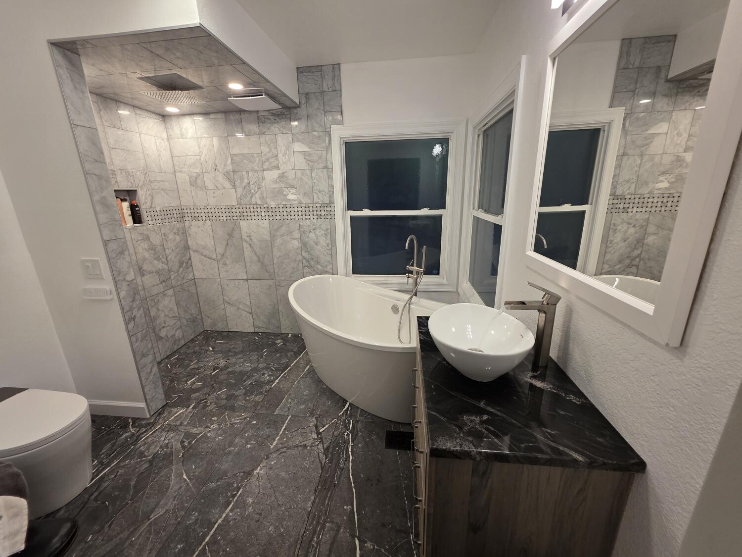 Marble shower, freestanding tub, and vessel sink