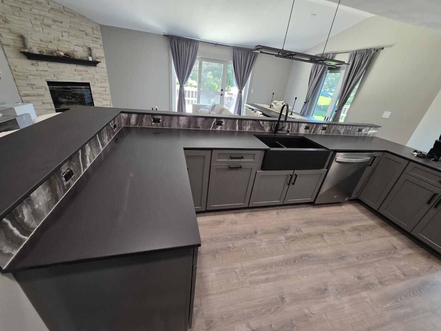 Gray kitchen with dark counters and stone backsplash