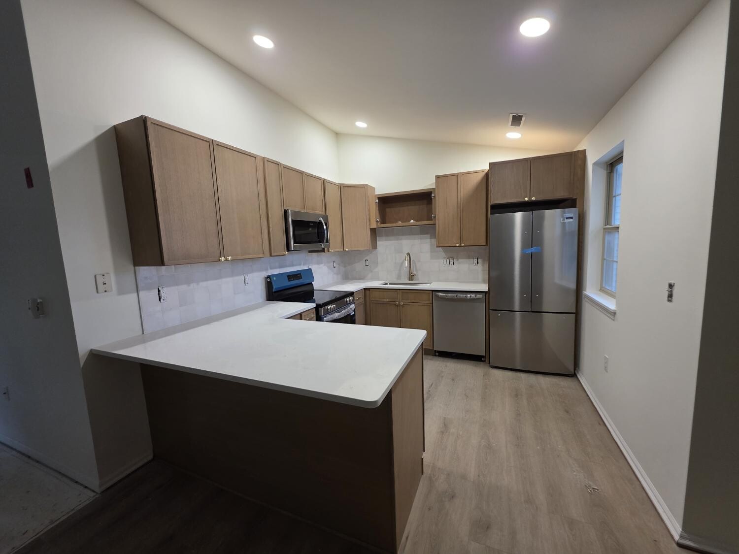 Light oak kitchen with white counters and peninsula
