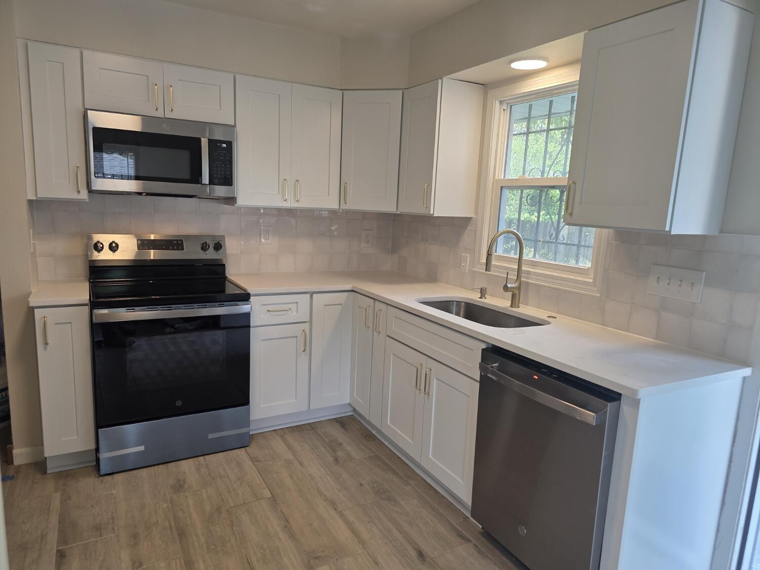 White L-shaped kitchen with gold faucet